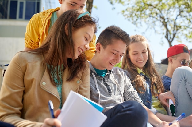 concepto de educación, escuela secundaria y gente - grupo de estudiantes adolescentes felices con cuadernos aprendiendo en el patio del campus