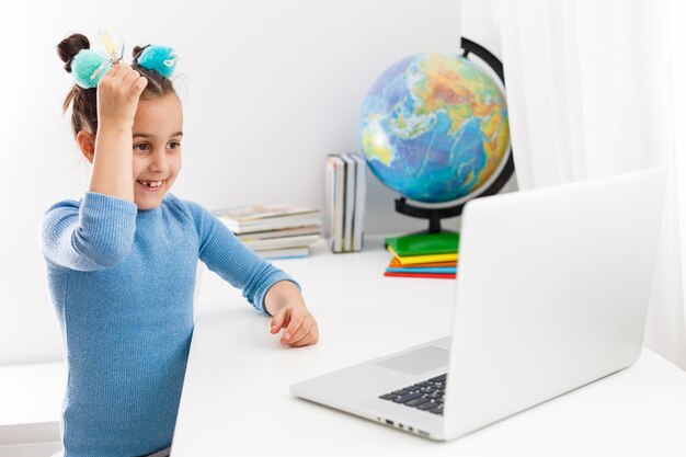 concepto de educación, escuela, tecnología e internet - niña estudiante apuntando a la computadora portátil con bombillas en la escuela