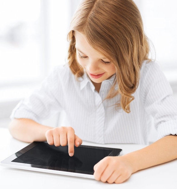 Concepto de educación, escuela, tecnología e internet - niña estudiante con tablet pc en la escuela