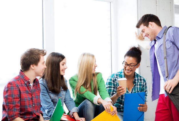 concepto de educación - estudiantes comunicándose y riendo en la escuela