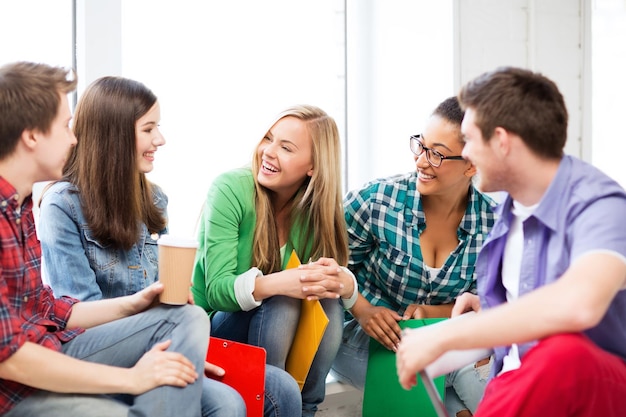 Foto concepto de educación - estudiantes comunicándose y riendo en la escuela