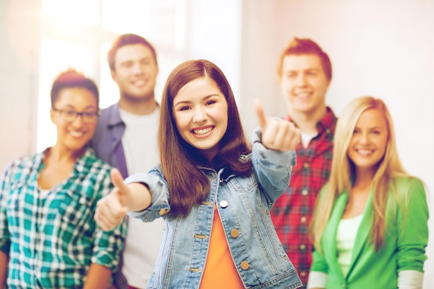 Foto concepto de educación - feliz equipo de estudiantes mostrando los pulgares para arriba en la escuela