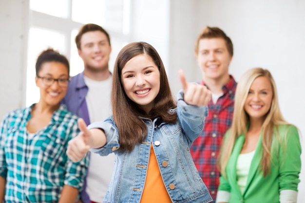 Foto concepto de educación - feliz equipo de estudiantes mostrando los pulgares para arriba en la escuela