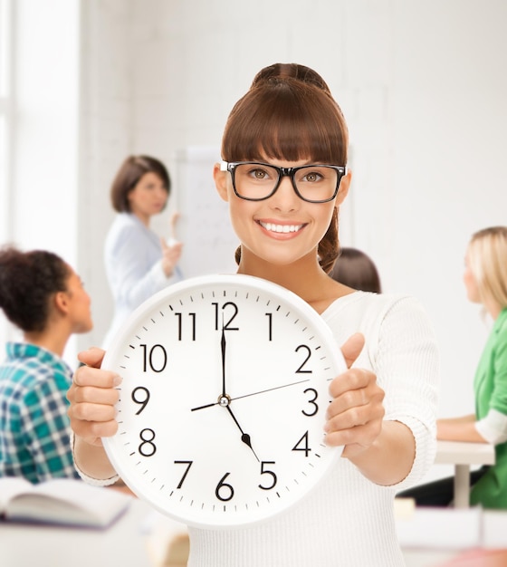 Concepto de educación y gestión del tiempo - estudiante atractivo que muestra el reloj