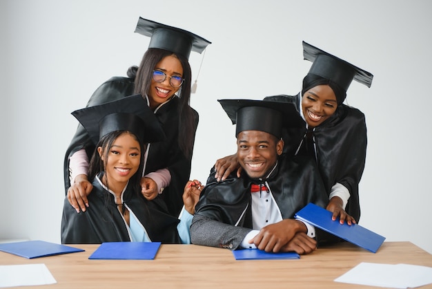 Concepto de educación, graduación y personas - grupo de estudiantes graduados internacionales felices en juntas de mortero y batas de soltero con diplomas