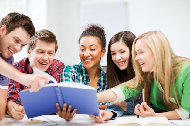 concepto de educación - grupo de estudiantes leyendo el libro en la escuela