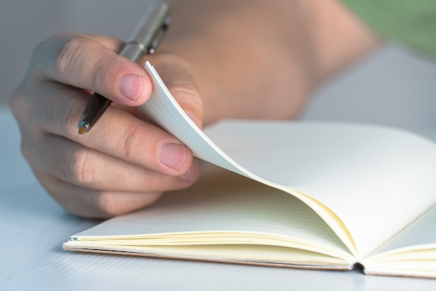 Concepto de educación Hombre de la mano escribir cuaderno sobre la mesa blanca