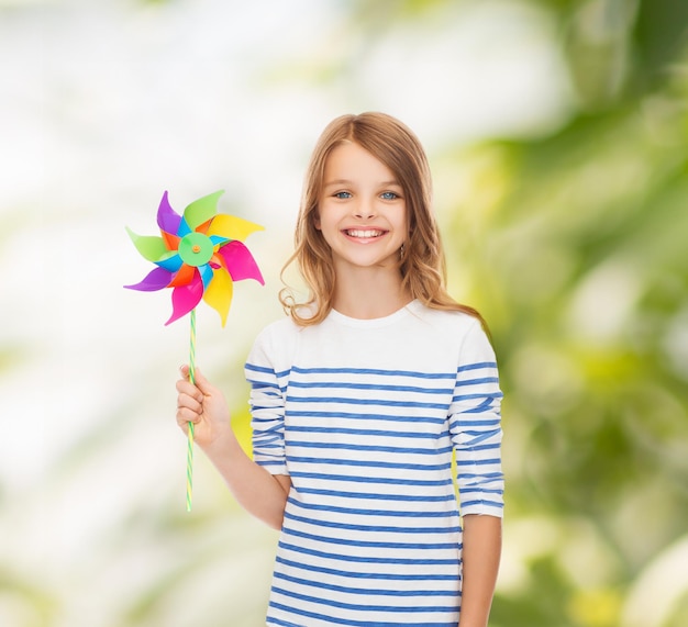 concepto de educación, infancia y ecología - niño sonriente con colorido juguete de molino de viento