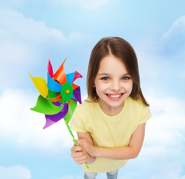 concepto de educación, infancia y ecología - niño sonriente con colorido juguete de molino de viento