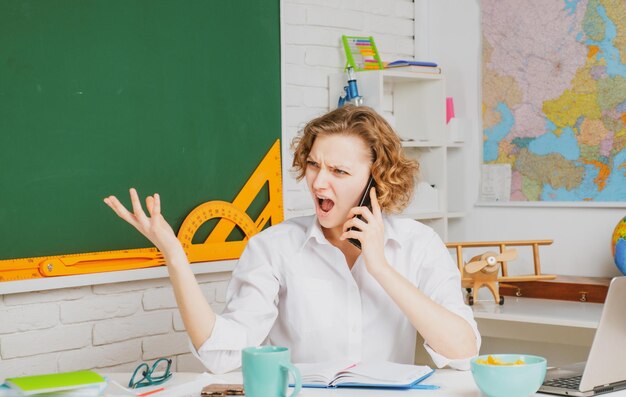 Concepto de educación maestro de escuela hablando por teléfono inteligente tutor enojado en el estudio y el aprendizaje en el aula