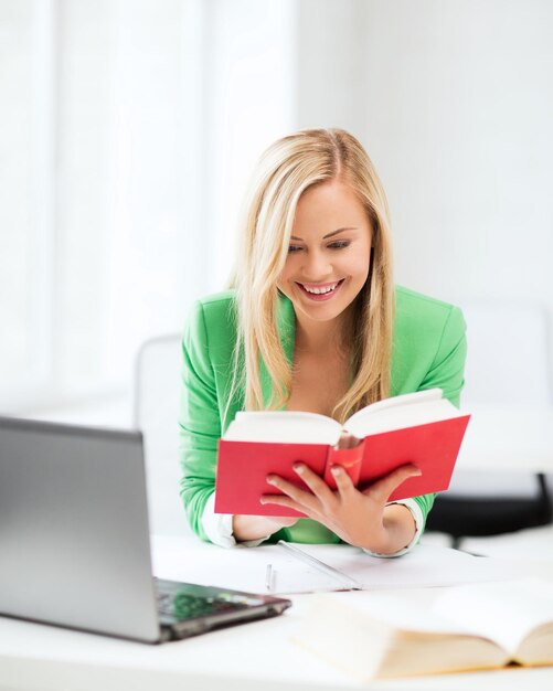 concepto de educación - niña estudiante sonriente leyendo un libro en la universidad