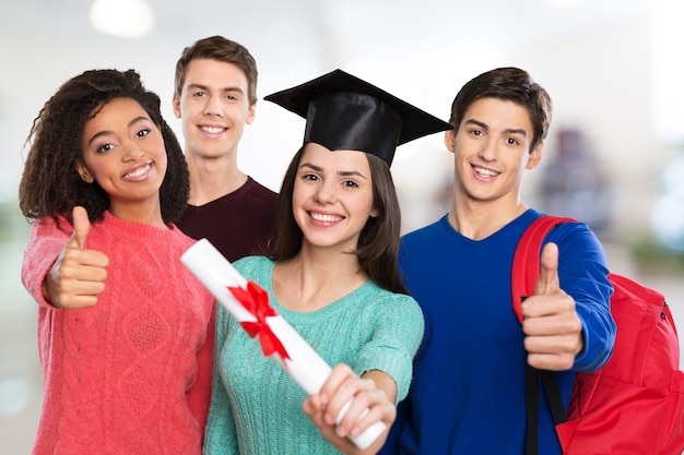 concepto de educación - niña feliz en la gorra de graduación con diploma y estudiantes