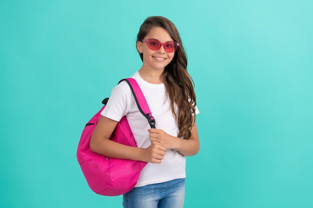 Concepto de educación. niño con gafas de sol sobre fondo azul. 1 de septiembre. infancia feliz. niño con mochila escolar. una adolescente sonriente lleva una mochila. De vuelta a la escuela. día del conocimiento.