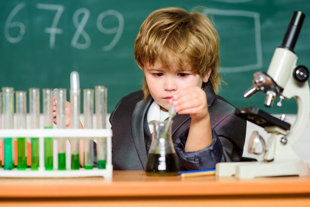 Concepto de educación Niño prodigio experimentando con química Tubos de ensayo de niño Química de líquidos Análisis químico Científico talentoso Niño estudia química Biotecnología y farmacia Alumno genio