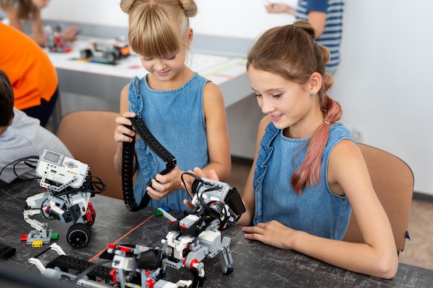 Foto concepto de educación, niños, tecnología, ciencia y personas - grupo de niños felices con robots de construcción de computadoras portátiles en la lección de la escuela de robótica