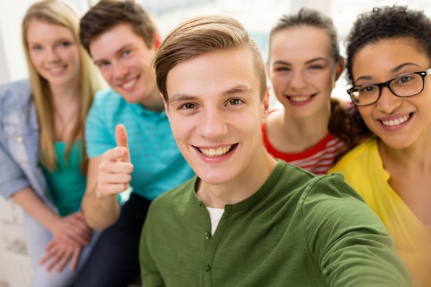 concepto de educación, ocio y tecnología - cinco estudiantes sonrientes tomando selfie en la escuela