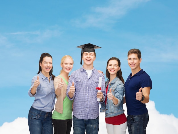 concepto de educación y personas - grupo de estudiantes sonrientes de pie con diploma y gorra de esquina mostrando los pulgares hacia arriba