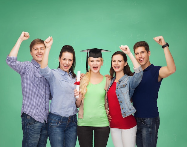 concepto de educación y personas - grupo de estudiantes sonrientes de pie con diploma y gorro de esquina