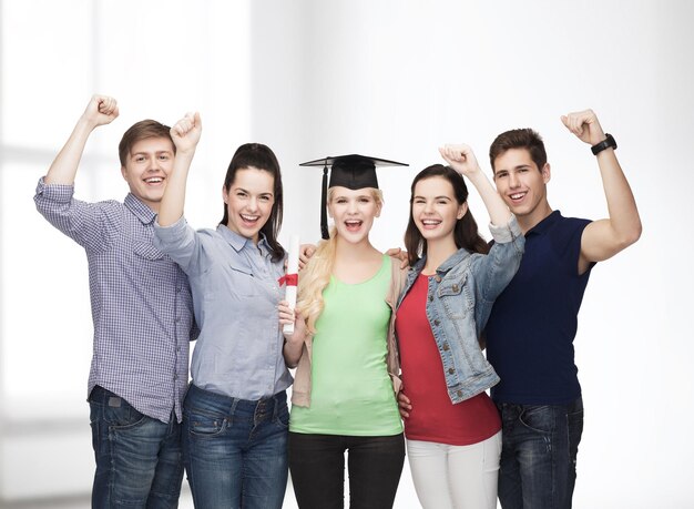 concepto de educación y personas - grupo de estudiantes sonrientes de pie con diploma y gorro de esquina