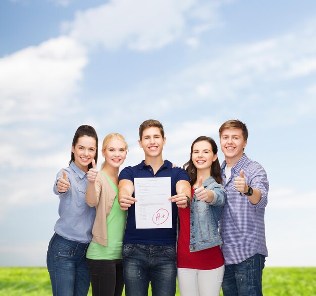 concepto de educación y personas - grupo de estudiantes sonrientes de pie y mostrando pruebas y pulgares hacia arriba