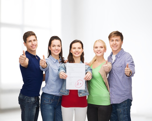 concepto de educación y personas - grupo de estudiantes sonrientes de pie y mostrando pruebas y pulgares hacia arriba