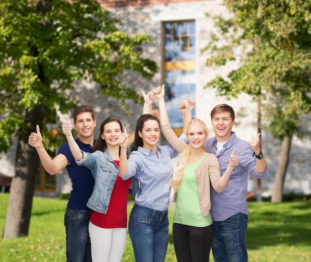 concepto de educación y personas - grupo de estudiantes sonrientes de pie y mostrando los pulgares hacia arriba