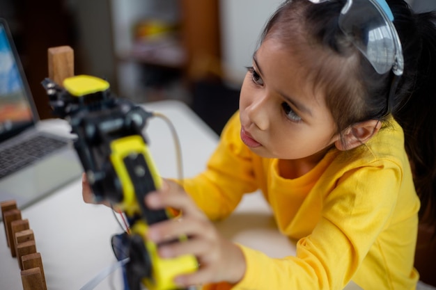 Concepto de educación STEM Los estudiantes asiáticos aprenden en casa codificando brazos robóticos en STEM matemáticas ingeniería ciencia tecnología código informático en robótica para conceptos de niños