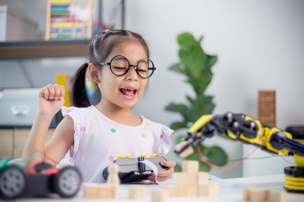 Concepto de educación STEM Los estudiantes asiáticos aprenden en casa codificando brazos robóticos en STEM matemáticas ingeniería ciencia tecnología código informático en robótica para conceptos de niños