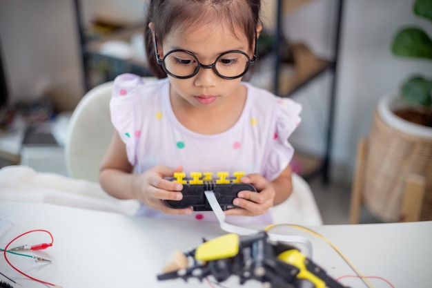 Concepto de educación STEM Los estudiantes asiáticos aprenden en casa codificando brazos robóticos en STEM matemáticas ingeniería ciencia tecnología código informático en robótica para conceptos de niños