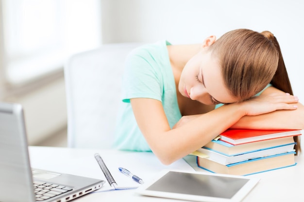 Concepto de educación y tecnología - estudiante cansado durmiendo en una pila de libros