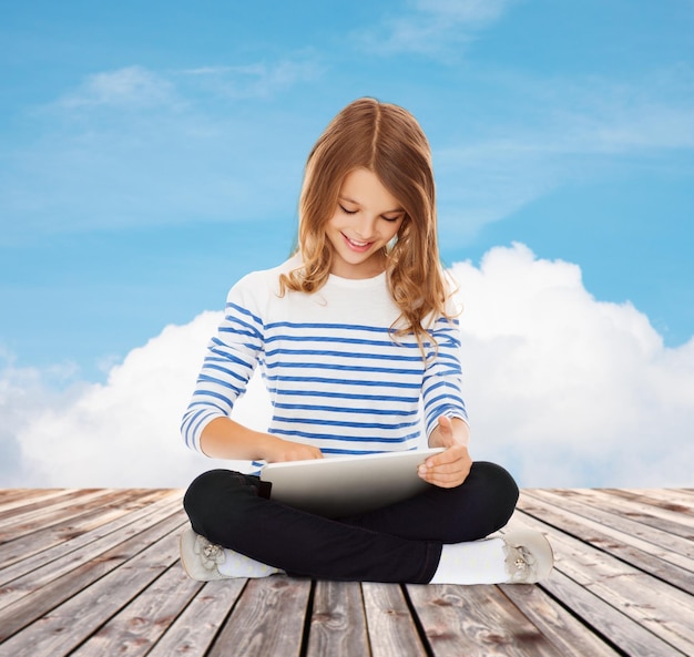 concepto de educación, tecnología, infancia y personas - niña estudiante feliz con tablet pc sobre el cielo azul y el fondo de la nube