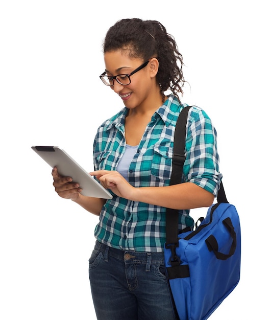 Concepto de educación, tecnología y personas - estudiante afroamericana sonriente en anteojos con tablet pc y bolsa