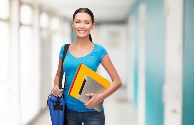 concepto de educación, tecnología y personas - estudiante sonriente con bolsa, carpetas y computadora de tablet pc de pie en el pasillo de la escuela