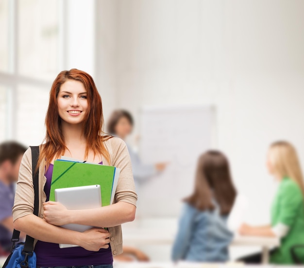 Concepto de educación, tecnología y personas - estudiante sonriente con bolsa, carpetas y computadora tablet pc de pie