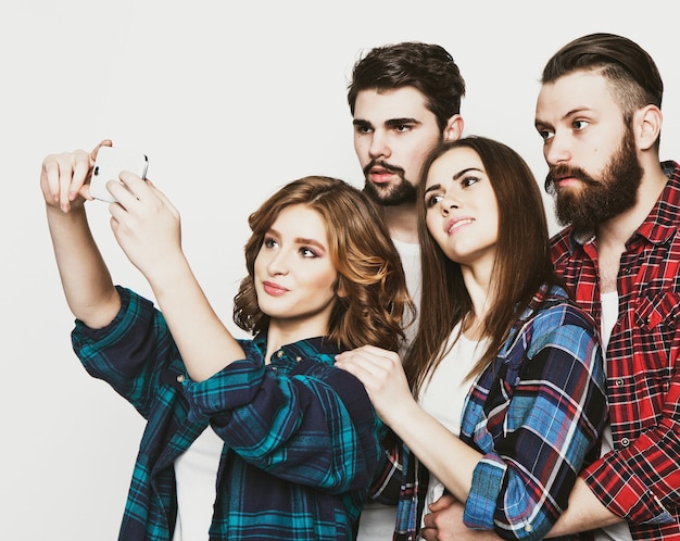 Concepto de educación, tecnología y personas: grupo de estudiantes tomando selfie con smartphone sobre fondo blanco. Tonificación de moda especial.