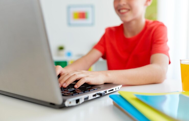 Foto concepto de educación, tecnología y personas - primer plano de un estudiante sonriente escribiendo en una computadora portátil en casa