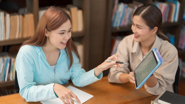 Concepto de educación universitaria Adolescente señalando gráfico en tableta para hacer preguntas con tutor