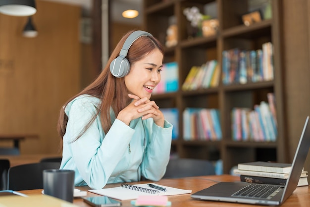 Concepto de educación universitaria Adolescente usa auriculares y ve un video tutorial de tutor en una computadora portátil