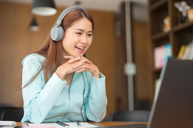 Concepto de educación universitaria Adolescente usa auriculares y ve un video tutorial de tutor en una computadora portátil