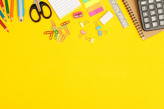 Concepto de educación vista superior cuadernos y accesorios de papelería en la biblioteca en la escuela fondo amarillo