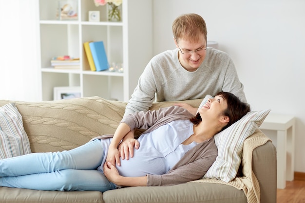 concepto del embarazo, la familia y las personas - esposa embarazada feliz con el marido en casa