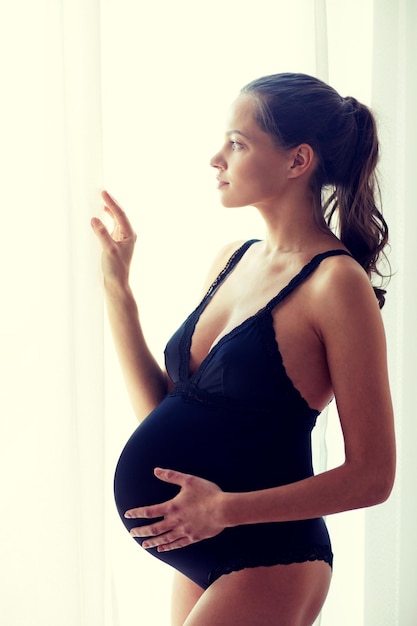 concepto de embarazo, maternidad, personas y expectativas - mujer embarazada feliz con una gran barriga desnuda en casa