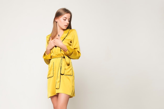 Concepto de emociones, personas, belleza, moda y estilo de vida - Foto de moda de mujer joven magnífica. Vestido amarillo brillante, albornoz. Chica posando. Foto de estudio