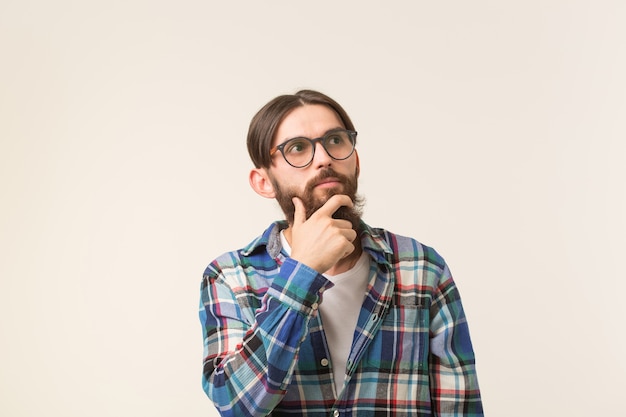 Concepto de emociones y personas - hombre hipster barbudo pensando en algo en el espacio en blanco.