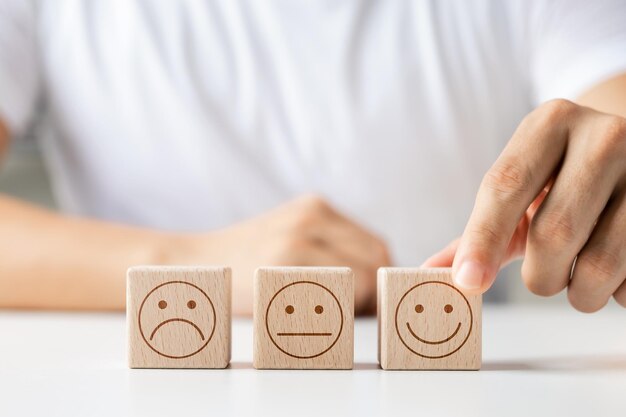 Concepto de encuesta de satisfacción del cliente mano del cliente selecciona cubo de madera con icono de cara sonriente mejor calificación de excelencia de servicio para la satisfacción