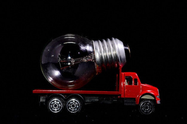 Concepto de energía eléctrica Camión rojo y bombilla sobre fondo negro