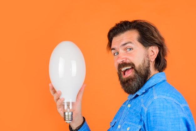 Concepto de energía y electricidad guapo en camisa de mezclilla con bombilla bombilla en mano joven