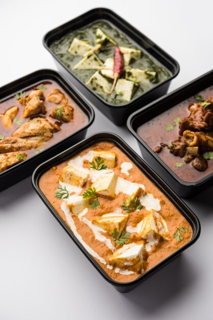 Concepto de entrega de alimentos en línea India paneer mantequilla masala y palak paneer, cordero y pollo al curry con roti y arroz en recipientes de plástico, alimentos como pollo con mantequilla, pollo