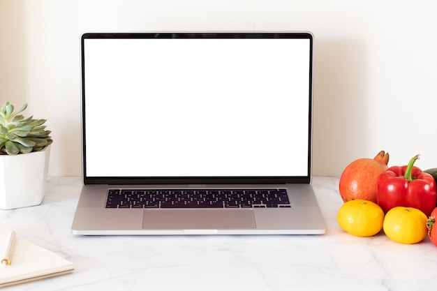 Concepto de entrega de alimentos en línea con portátil de pantalla en blanco blanco. Servicio de entrega de comestibles. Oficina en casa.