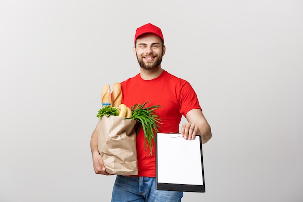 Concepto de entrega: apuesto hombre de mensajería de entrega de comestibles del Cáucaso en uniforme rojo con caja de supermercado